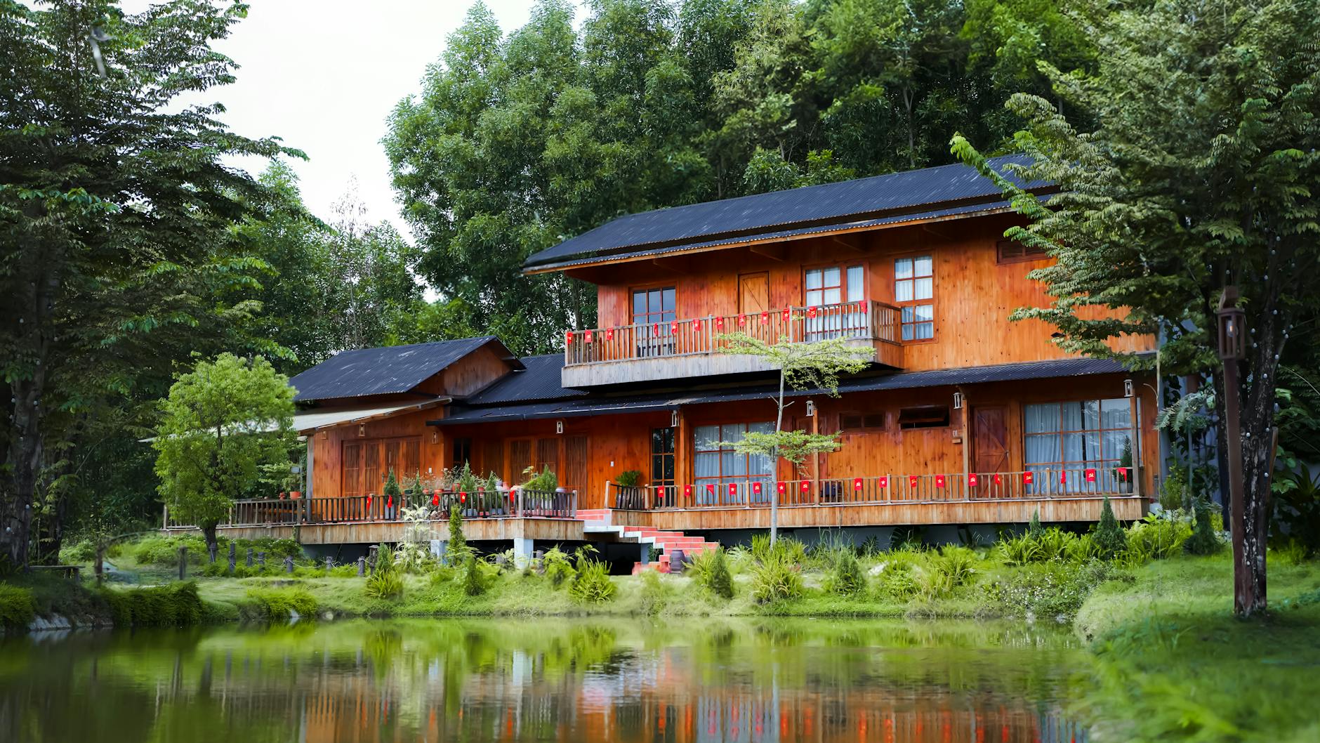 Drewniany dom nad mazurskim jeziorem otoczony bujną zielenią