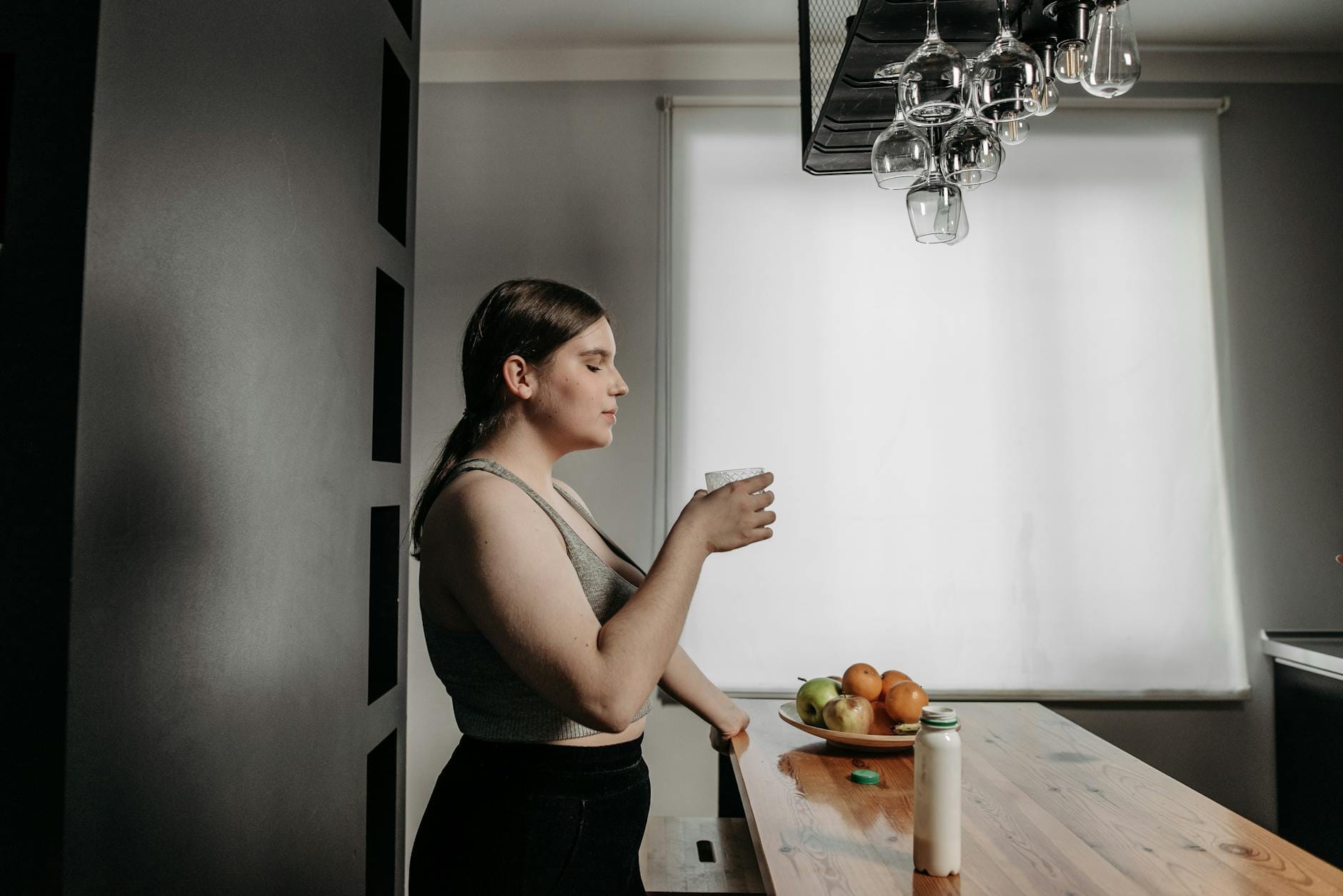 Energia w ciągu dnia bez kawy: jak wykorzystać rytm dobowy do naturalnych zastrzyków mocy Kobieta w kuchni pije zdrowy smoothie jako naturalny zastrzyk energii