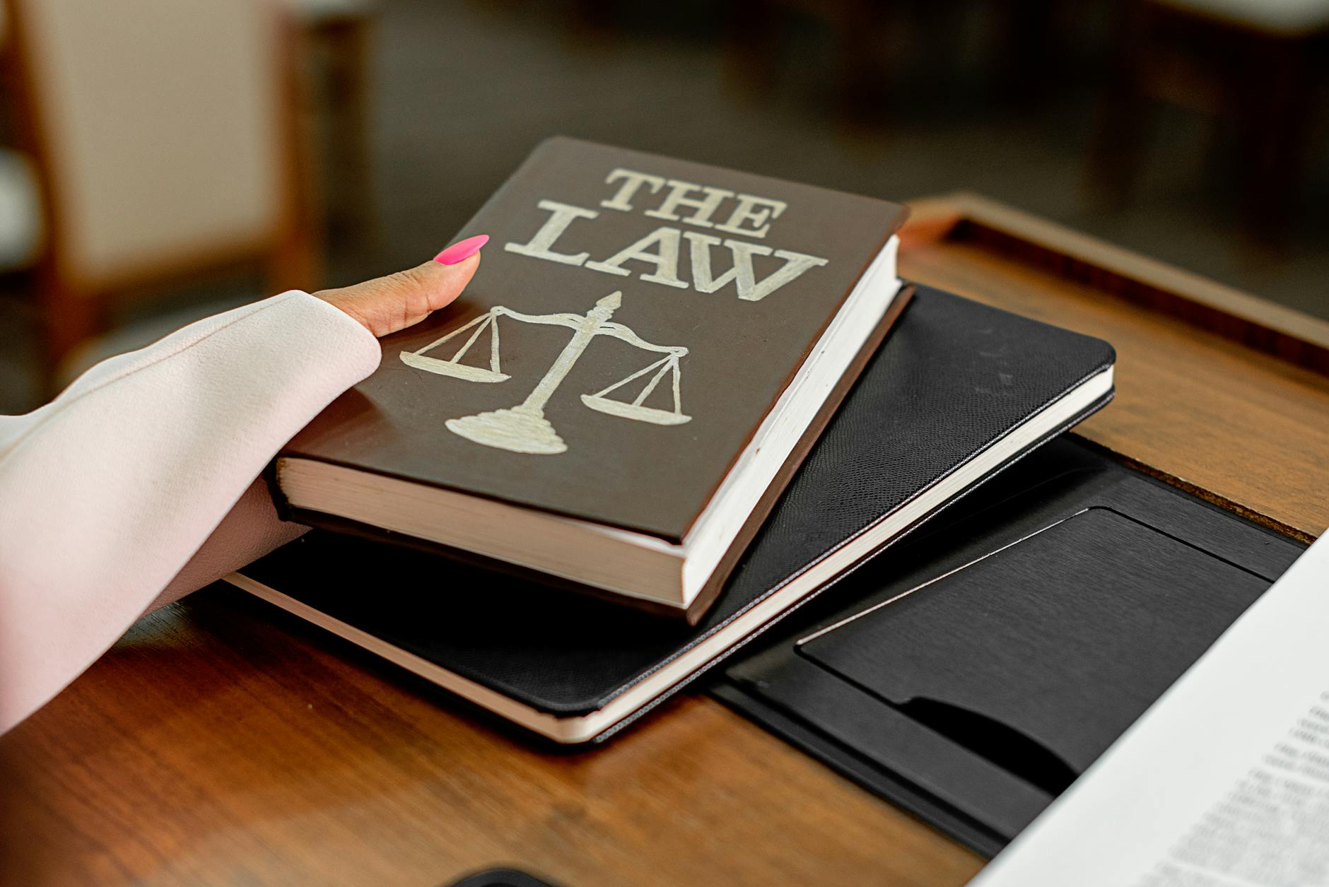 Jak przygotować statut szkoły zgodnie z aktualnym prawem oświatowym krok po kroku Księga z napisem The Law i waga Temidy na drewnianym biurku