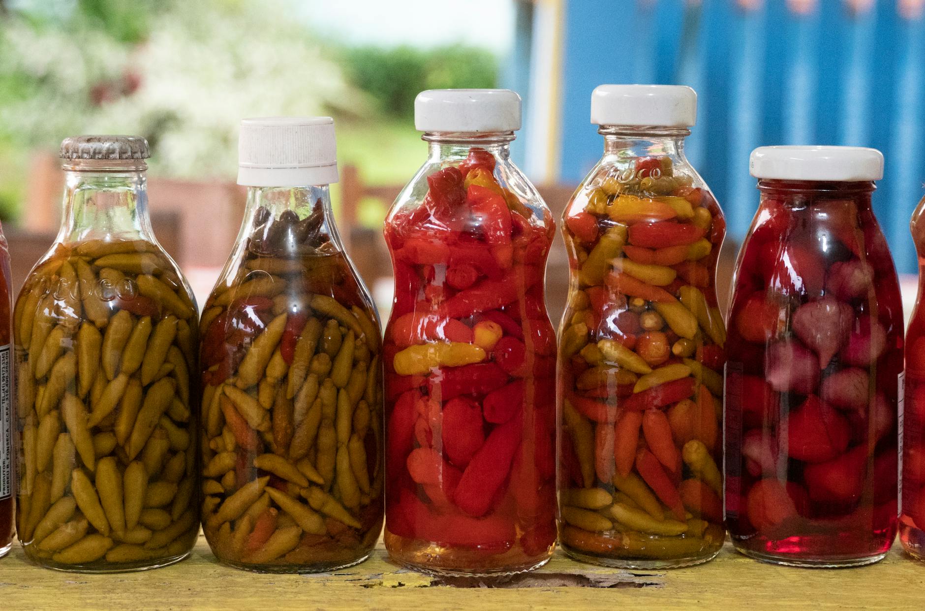 Zbliżenie kolorowych marynowanych papryczek chili w szklanych butelkach